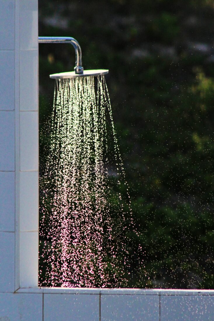Buitendouche met glazen wand in de tuin